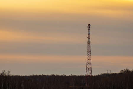 silhouette of a cell tower in the forest against the sunset sky. communication in the forest