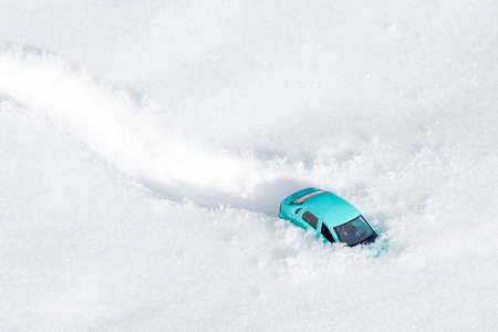 a car that flew off the track got stuck in the snow, a toy car on the roof in the snowの写真素材