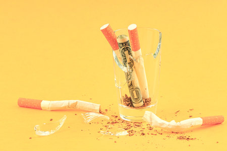 broken broken glass for alcohol in which a rolled dollar and broken crumpled cigarettes. throw away cigarettesの写真素材