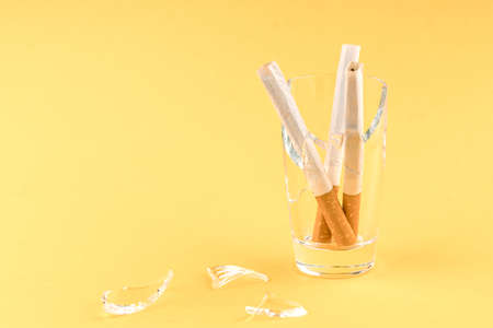 three cigarettes, filter down, are stacked in a glass beaker. smoking control concept