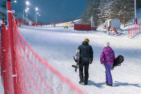 a man and a woman climb in the winter on the ski slope carry