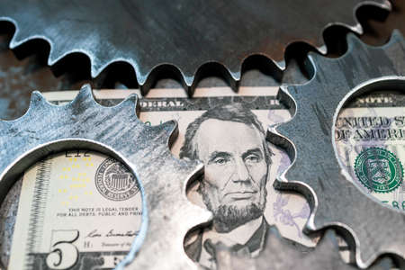 metal gears surround the portrait on a five-dollar bill. how money worksの写真素材