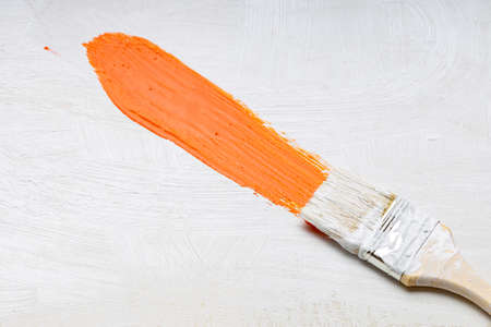 a brush with white bristles leaves an orange trace of paint, a painter's brush and canvasの写真素材