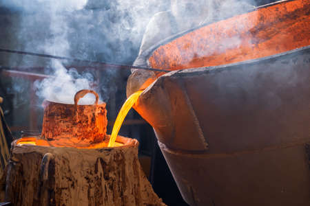 the process of pouring molten metal into a mold, smoke and heat in the workshopの写真素材