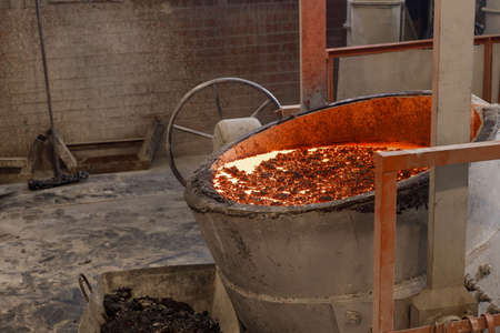 foundry, molten metal vat ready for casting. red liquid metal and a crust on top