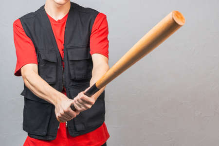 a baseball bat in the hands of a young white man in a black vest. strong hands grip the batの写真素材