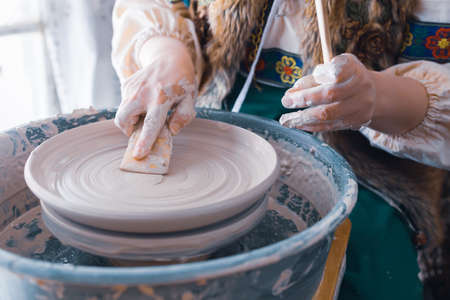 close-up of the potter's hands with a wooden spatula to align the plate during the production process. potter at workの写真素材