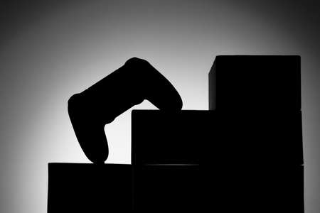gamepad silhouette between the degrees of the pedestal leading up, background gray gradientの写真素材