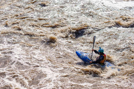 a difficult section on the river is overcome by a man on a kayak. fighting nature and testing oneself for strengthの写真素材