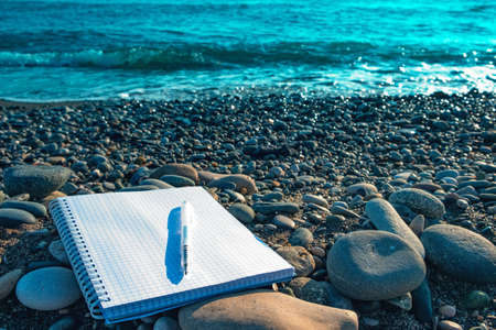 blank notebook on the seashore and fountain pen. notebook for notes at sea. writer on vacationの写真素材