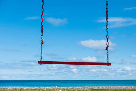 empty wooden swing on the background of the sea horizon on the beach. difficult season lack of touristsの写真素材