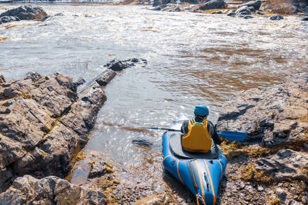 kayak and a man with a paddle on the background of the river. spring landscape on the river. active rest on the rutting riverの写真素材