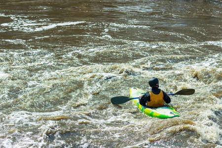 a man floating on the river on a kayak. stormy water is dirty around the boat. active recreation on the riverの写真素材