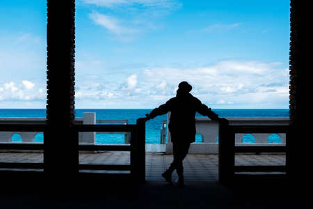 man in a hat looks at the sea, silhouette of a man. there are no tourists, the season is over. lonely man and the seaの写真素材