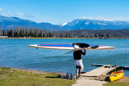 the rower carries the boat on his shoulder to the lake. beautiful landscape of highlands. blue sky...