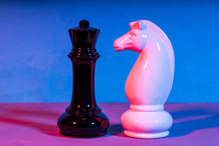 two chess pieces white and black illuminated by different light sources. double shadows neon color.の写真素材