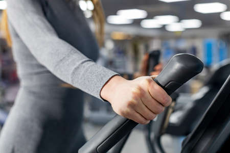 female hand on the handle of the simulator. workout in the gym. background blurredの写真素材