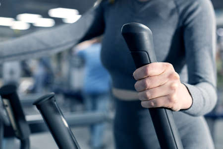 part of the girl's body holding the handle of the simulator. hand of a girl engaged in a gymの写真素材