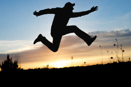 silhouette of a running man on the background of sunset on the grass. quickly run up