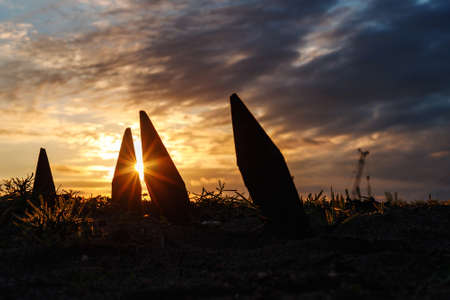 sharp corners stick out from the ground in the form of silhouettes against the sunset. sun between formsの写真素材