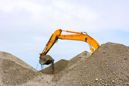 part of the excavator dripping sandy soil, bulk material. sand is poured out of the pile at the...