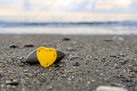 yellow plastic heart on the seashore, stone and heart. love for the seaの写真素材