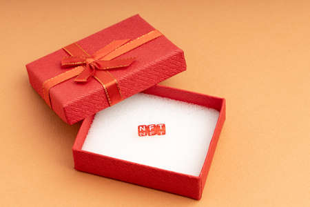 in an open red gift box, cubes with the letters NFT. blockchain as a gift