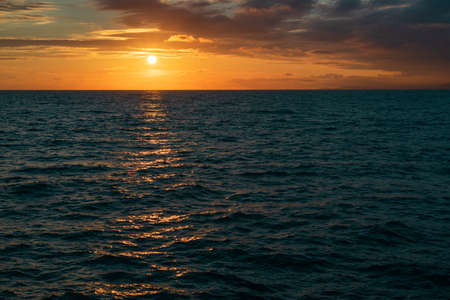 the setting sun in the evening on the sea, the path of the sun on the sea surface. orange color sunset on the seaの写真素材