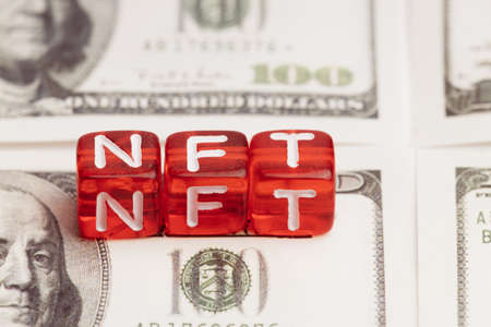 non-fungible NFT tokens written on red cubes. background mto dollar bills stacked in a rowの写真素材