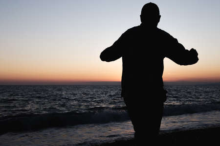 a man walking joyfully along the shore rejoices at the sea he has seen. silhouette of a man on the seaの写真素材
