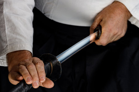 the warrior's hands draw the sword from its scabbard, the steel sword gleams. samurai and his weaponsの写真素材