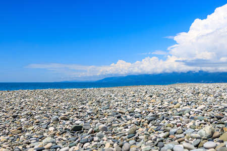 pebble beach against the blue sky and clouds. many round stonesの写真素材