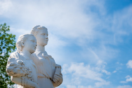 sculpture of the Soviet period, mother and daughter look into the future against a blue sky with clouds, view from below.の写真素材