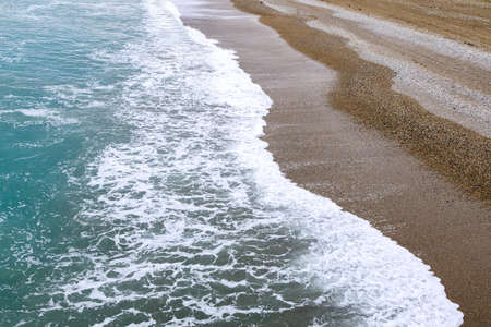 stripes on the sea coast during a storm, blue sea water on the shore. foam and pebblesの写真素材