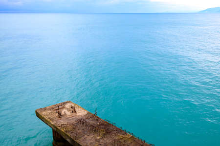 part of an abandoned pier with dangerously protruding metal elements against the backdrop of sea blue water. skyline and part of the old pierの写真素材