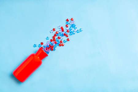 red vase on a blue fabric surface. plastic stars pour out of a red vase, the concept of a festive eventの写真素材