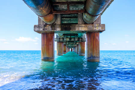 under the old pier, seascape during the day. sea water old concrete pier supports