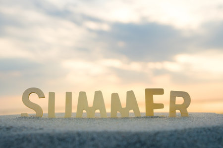 summer word from wooden letters, the letters are inserted into the sand against the background of the sea and the orange sky. summer day conceptの写真素材