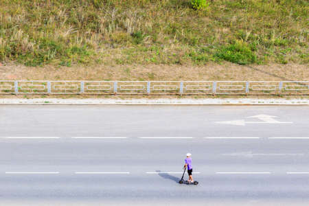 the boy rides a scooter on the road and looks back. scooter ride on the trackの写真素材