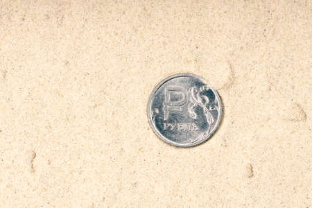 one ruble on the sand, one ruble coin with the symbol of the ruble among the sand. sand background