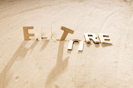 wooden letters on the sand made up the word future, broken future. the letters fell in the word, the future brokeの写真素材