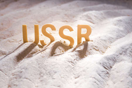 word from wooden letters USSR, old country in the sand. country stuck in the sandの写真素材