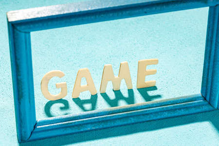 the word game is collected from wooden letters on a blue background. game within the rules