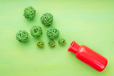 green wicker balls are scattered over a green surface and a red vase, top view. festive fireworks imitationの写真素材