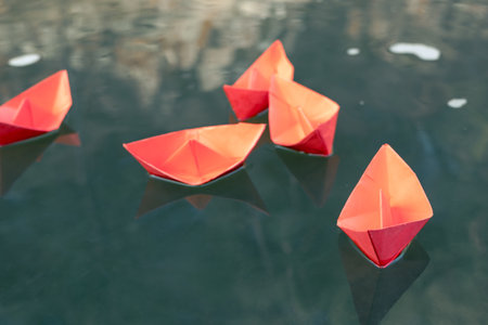 red paper on ships green water. five origami ships