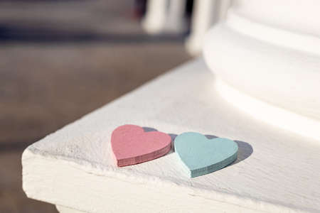 on the corner of the white concrete fence are two wooden hearts blue and red. blurred backgroundの写真素材