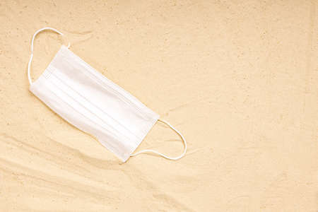 a white medical mask is on the sand. lying mask on the sand, drought and diseaseの写真素材
