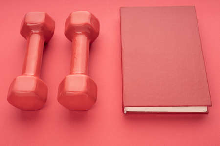 red hardcover book and red dumbbells on a red background. knowledge and powerの写真素材