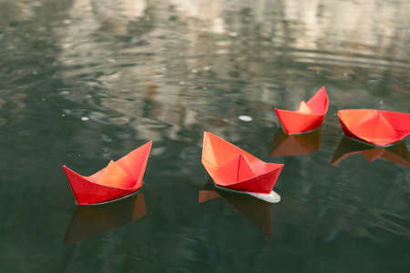 paper red ships on the river. four origami boats on the water