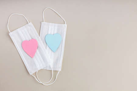 two medical masks lying one on top of the other. wood hearts on masks. protection and free space for...